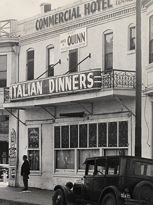 View of the Commercial Hotel building. A sign advertising Italian dinners is seen on building.