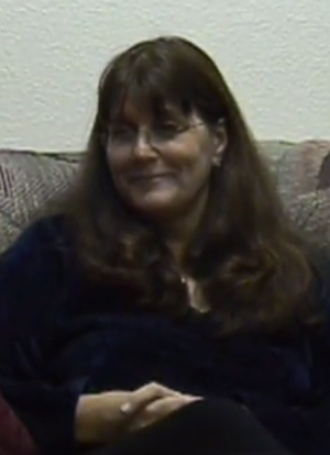 A smiling woman sits in a chair